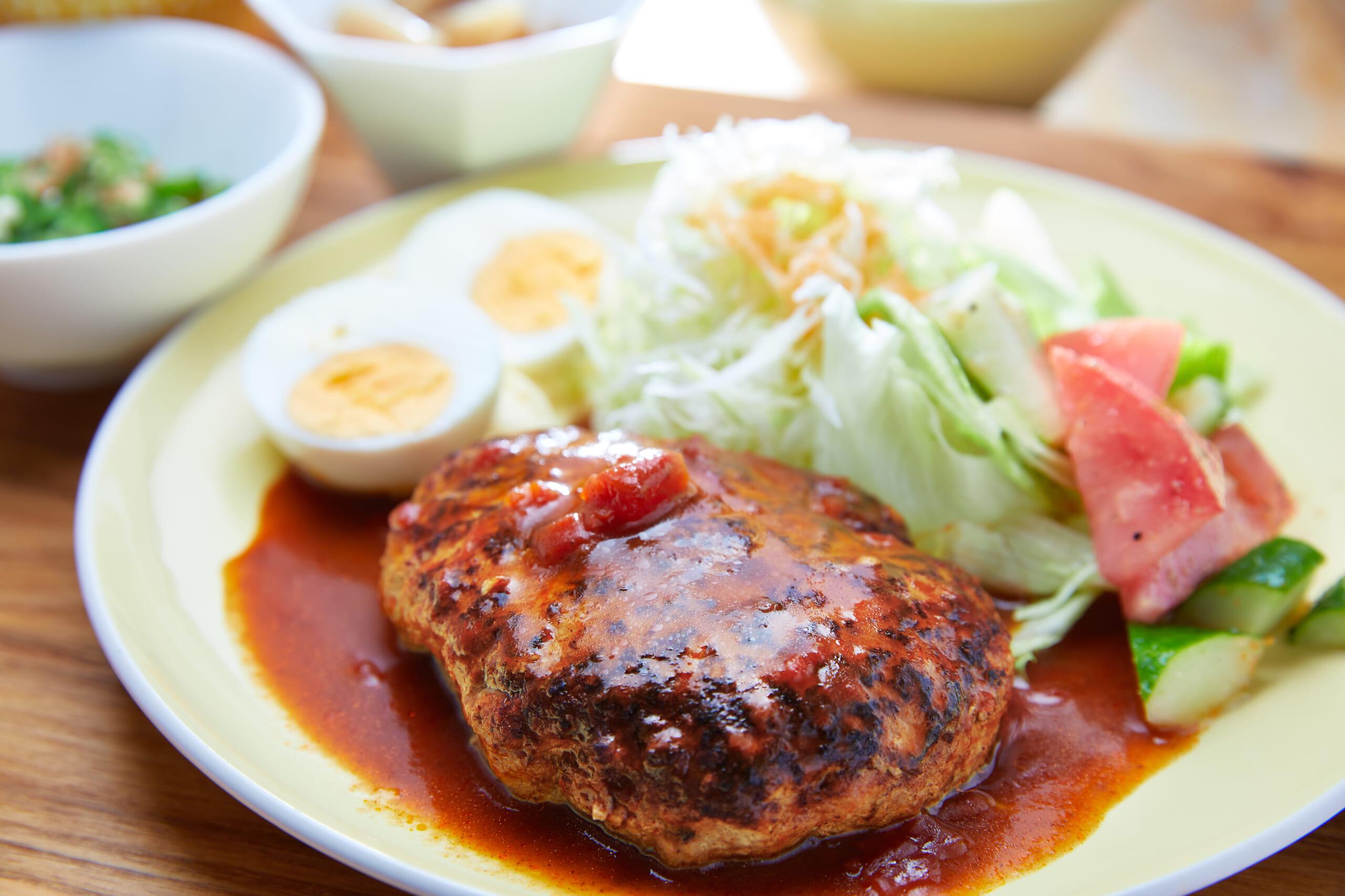 こたま食堂の日替わりランチ。ハンバーグに千切りキャベツ、ゆで卵、小鉢が添えられた定食