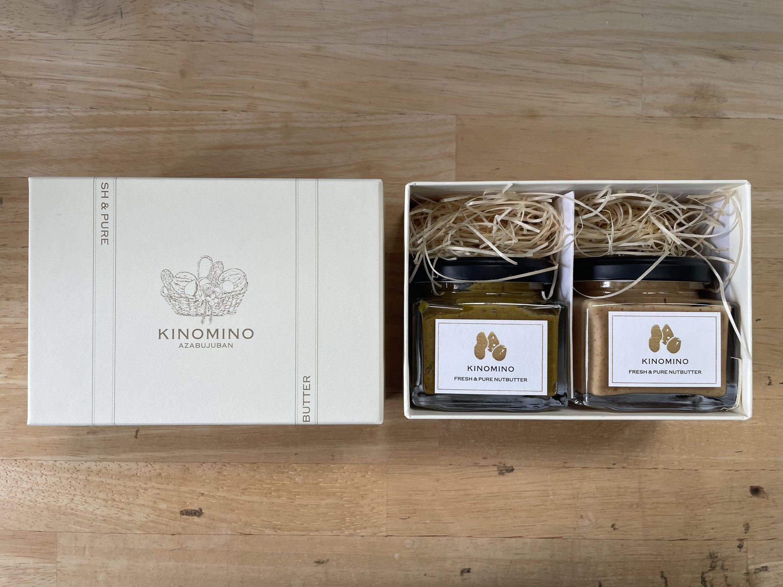 KINOMINOのギフトボックス。蓋にロゴの箔押し、木毛の緩衝材の上にナッツバター2瓶が収まっている